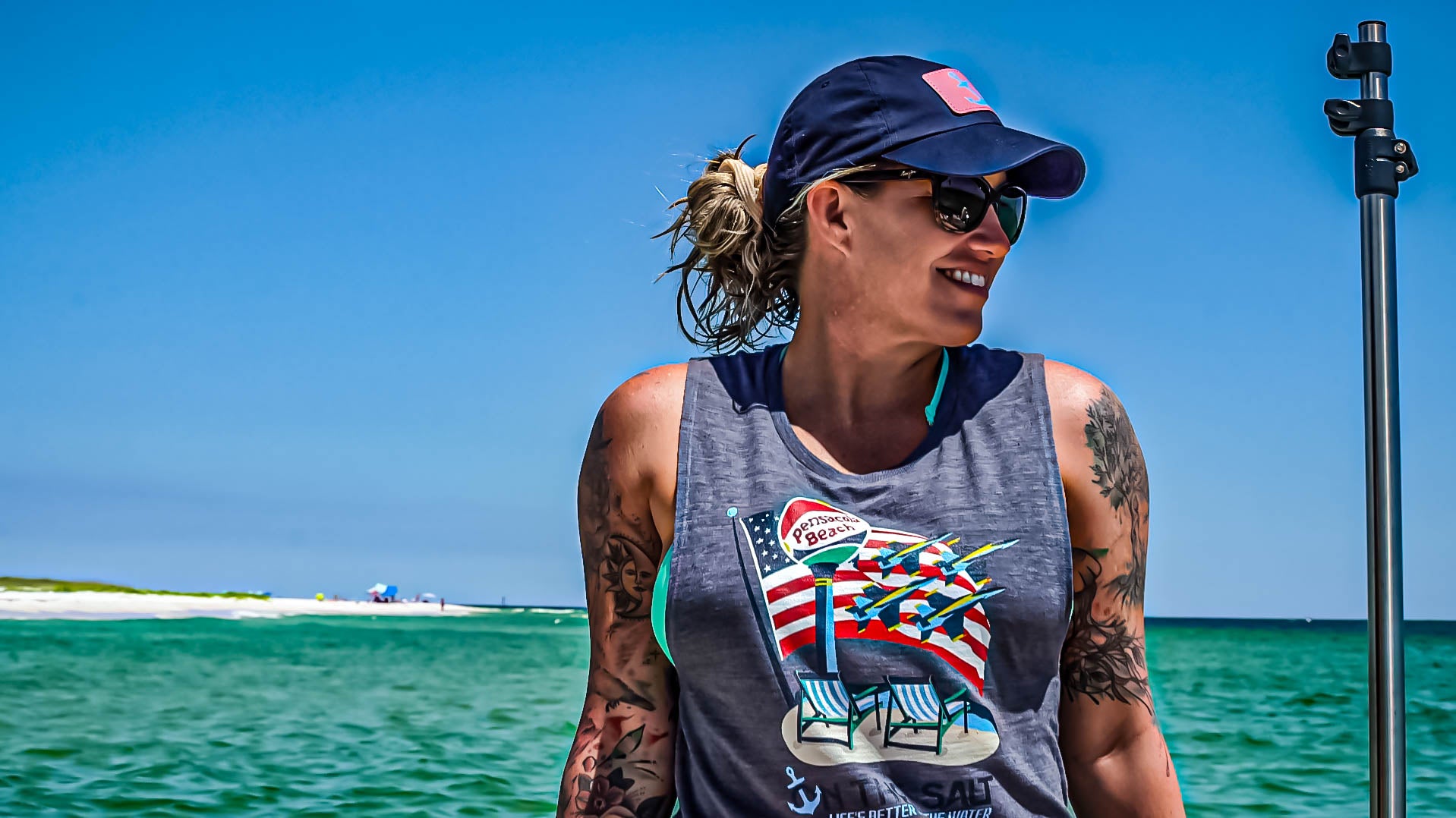 Person wearing a tank top with a graphic design by the water