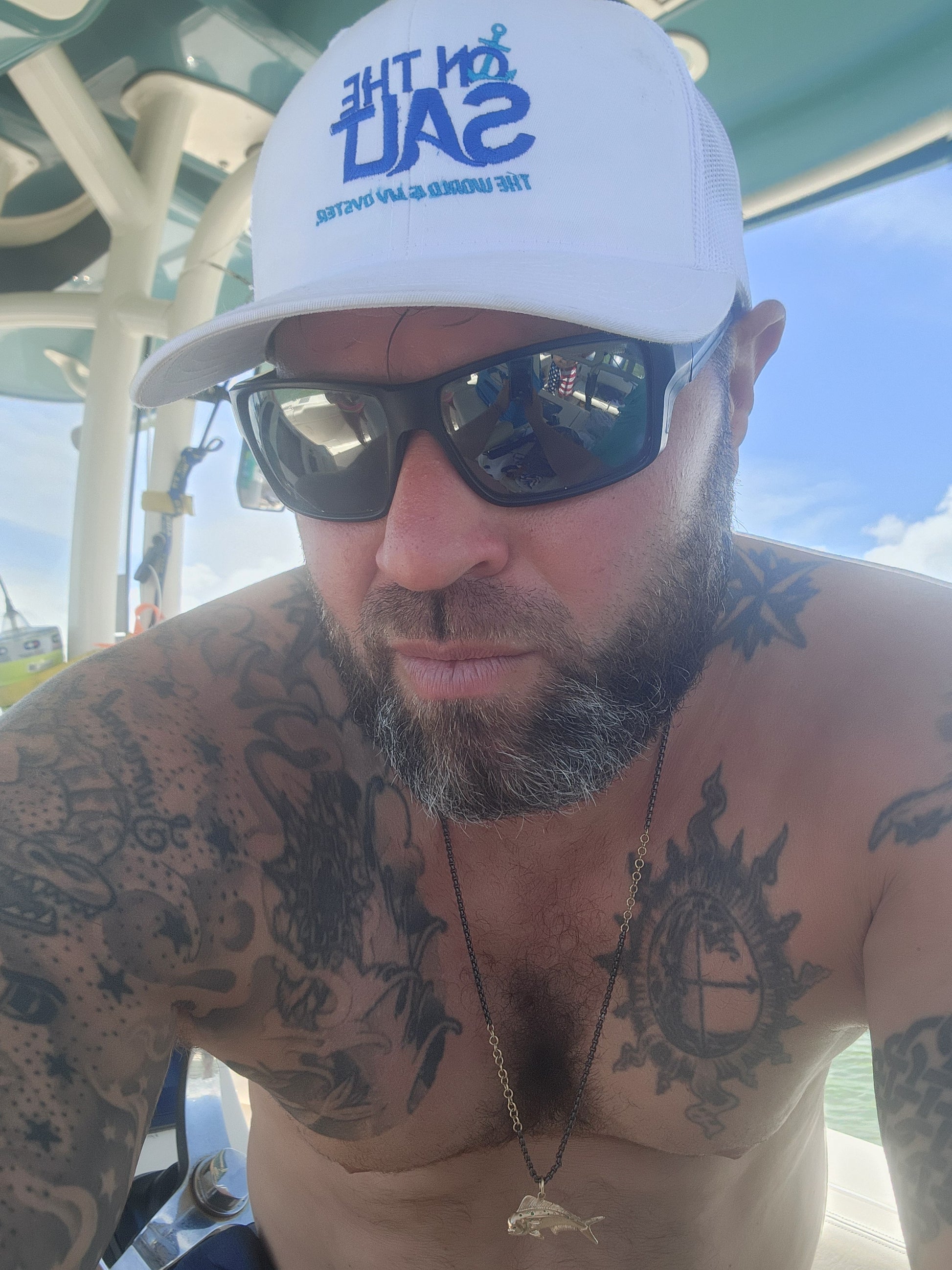 Man with tattoos wearing a white cap and sunglasses outdoors
